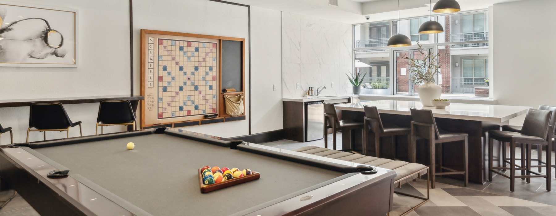 Spacious and well lit game room with billiard table and large windows 