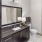 Large well lit bathroom with large mirror and brown cabinets 